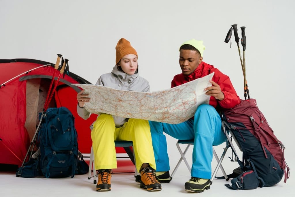 couple looking at map in front of tent and other gear