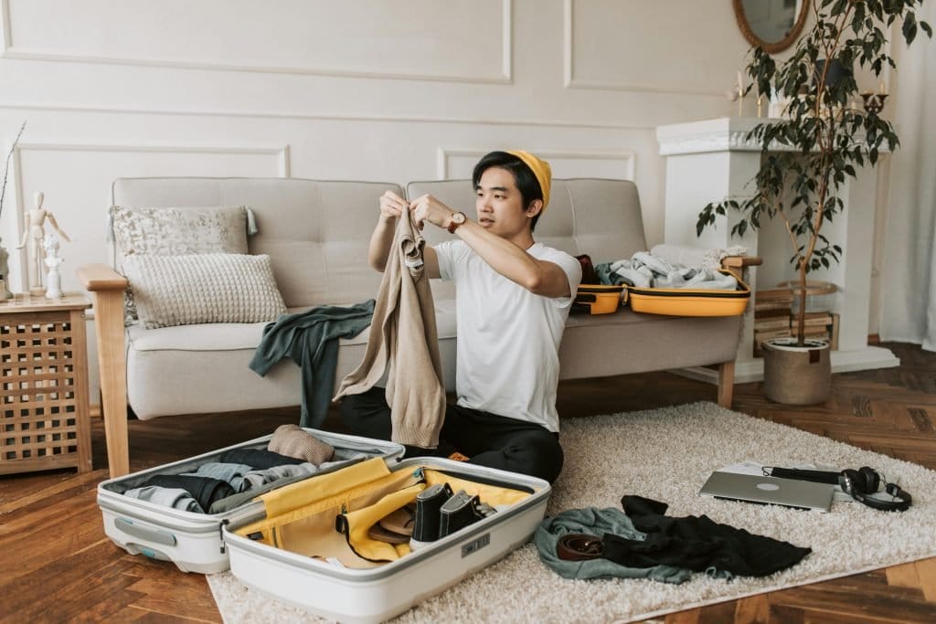 man packing suitcase on the floor in living room