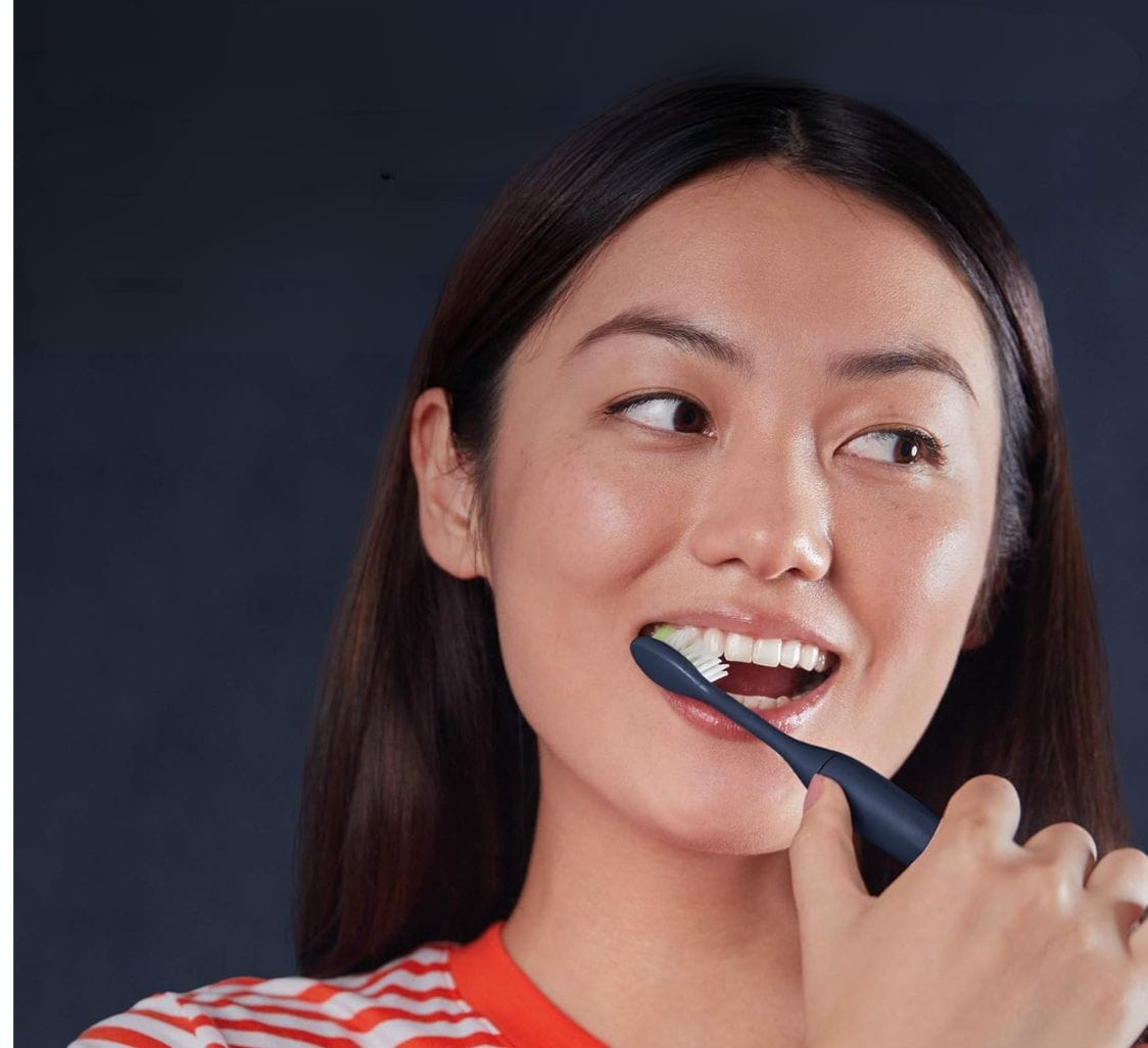 a woman brushing teeth with a electric toothbrush